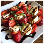 A vibrant Balsamic Strawberry Caprese salad with fresh strawberries, mozzarella, basil, and balsamic glaze.