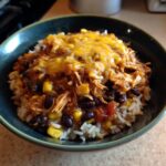 A flavorful Chicken Enchilada Bowl featuring rice, chicken, black beans, corn, and melted cheese.