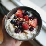A delicious Cottage Cheese Protein Bowl topped with fresh berries (strawberries, raspberries, blueberries, blackberries) and nuts.