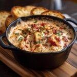 Creamy Chicken Parmesan Soup served in a cast iron skillet, garnished with herbs and bacon, alongside toasted bread.
