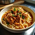 A bowl of Creamy Chicken Ramen with shredded chicken and green onion garnish.