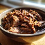 Close-up of tender Crockpot Garlic Butter Beef in a bowl, ready to serve.