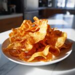 Pile of golden Crunchy Cottage Cheese Chips on a white plate, showcasing their crispy texture.