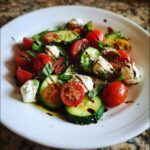 A vibrant Cucumber Caprese Salad with fresh cucumbers, tomatoes, mozzarella, and basil, drizzled with balsamic glaze.