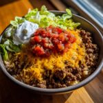 A vibrant Easy Taco Rice Bowl with seasoned ground beef, rice, cheese, salsa, lettuce, and sour cream.