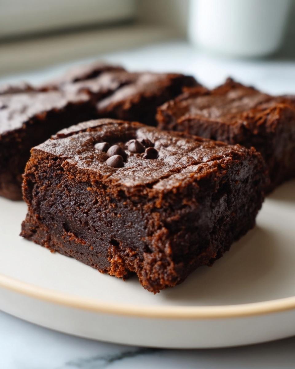 Close-up of flourless greek yogurt brownies on a plate, topped with chocolate chips.
