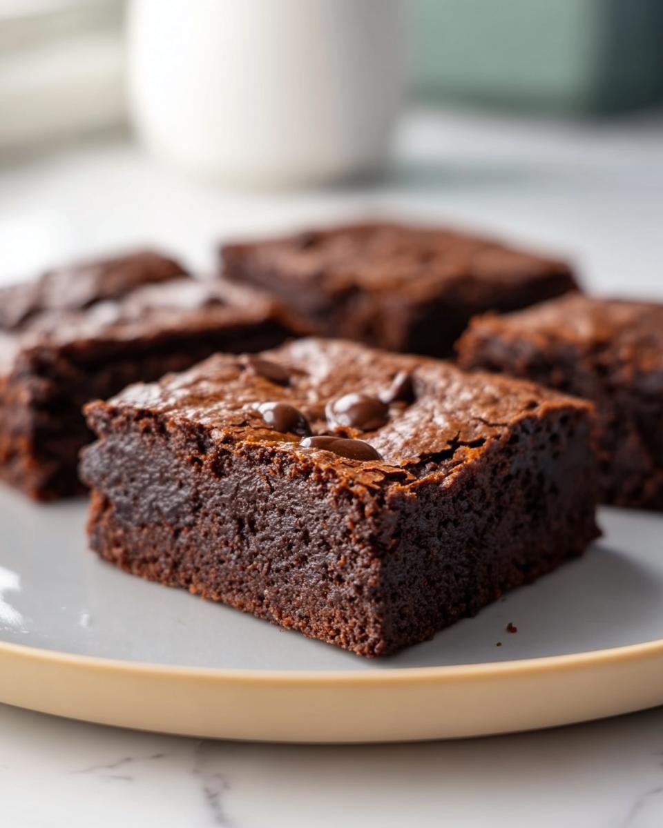Close-up of flourless greek yogurt brownies on a plate, topped with chocolate chips.