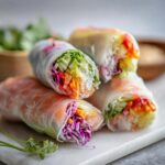 Stack of vibrant Fresh Spring Rolls filled with vegetables and rice noodles, wrapped in translucent rice paper.