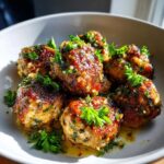 A bowl of glistening Garlic Butter Meatballs, garnished with fresh parsley.