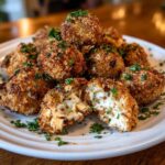 A plate of golden-brown Goat Cheese & Honey Bites, garnished with fresh parsley, one bite cut open to show the creamy filling.