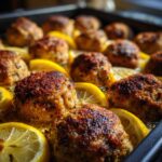Close up of Greek Chicken Meatballs with Lemon slices on a baking sheet, ready to serve.