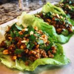 Three ground beef lettuce wraps topped with cilantro and peanuts, ready to eat. A tasty and quick meal!
