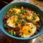 A vibrant Ground Beef Protein Bowl with soft-boiled eggs, ground beef, and green onion garnish.