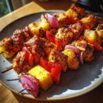 Close-up of Hawaiian Chicken Pineapple Kebabs with chicken, pineapple, red pepper, and red onion on a plate.