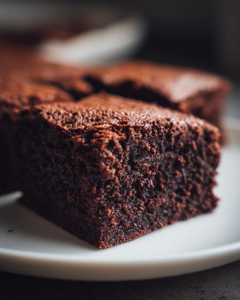 A close-up shot of a Healthy 87 Calorie Brownie on a white plate, showcasing its rich, dark chocolate texture.