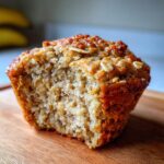 Close-up of a Healthy Banana Oatmeal Muffin with a bite taken out, showing the texture and ingredients.