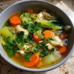 A bowl of Hearty Bokchoy Chicken Soup, featuring chicken, bok choy, carrots, celery, and fresh parsley.