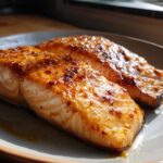 Two glistening Hot Honey Salmon fillets on a plate, showcasing the caramelized glaze and flaky texture.