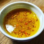 A bowl of vibrant yellow Immune Boosting Broth with spices, ready to enjoy.