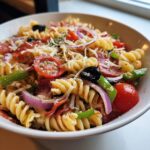 Close-up of a vibrant Italian Pasta Salad with rotini, pepperoni, tomatoes, olives, peppers, onions, and cheese.
