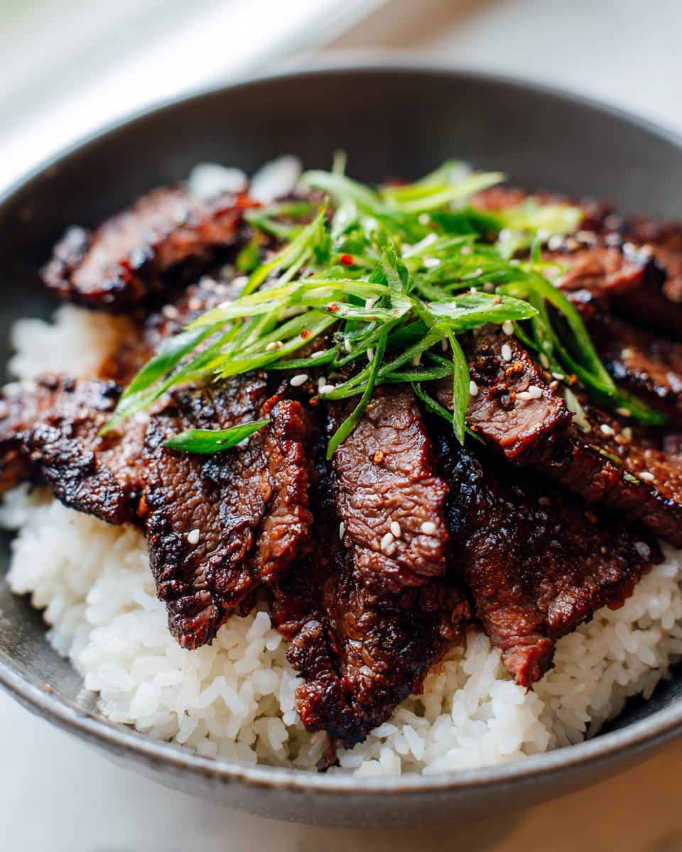 A delicious bowl of Korean BBQ Steak Rice topped with green onions and sesame seeds.