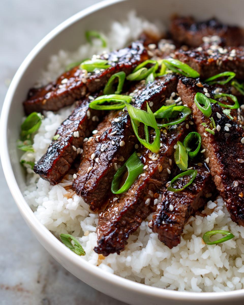 Close-up of Korean BBQ Steak Rice in a bowl, topped with scallions and sesame seeds.