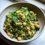 A bowl of Lemon Herb Quinoa Chickpeas salad with fresh herbs like mint and dill.