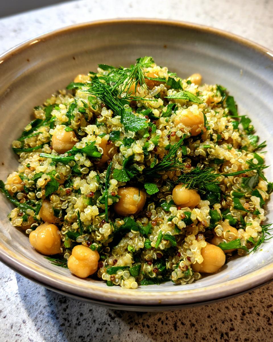 A bowl of Lemon Herb Quinoa Chickpeas salad, featuring fresh herbs, quinoa, and chickpeas.