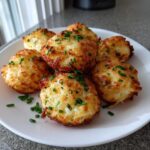 A plate of golden-brown Mashed Potato Puff Bites, garnished with fresh chives.