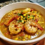 A bowl of Orleans Shrimp and Corn Bisque, garnished with fresh herbs and spices.