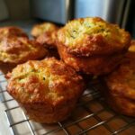 Close-up of golden brown Parmesan Zucchini Muffins cooling on a wire rack.