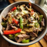 A flavorful Philly Cheesesteak Bowl filled with steak, peppers, onions, mushrooms, and melted cheese.