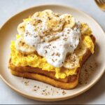 Toast topped with scrambled eggs, yogurt, and banana slices, a delicious example of Protein Breakfast Recipes.