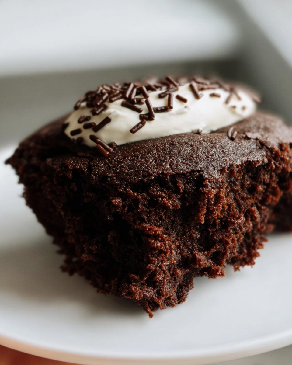 Close-up of a moist protein brownie topped with whipped cream and chocolate sprinkles.