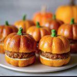 Close-up of Pumpkin-Shaped Sliders Halloween on a plate, styled to look like pumpkins with green stem decorations.