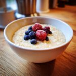 A bowl of creamy Quinoa Pudding topped with fresh blueberries, raspberries, and blackberries.
