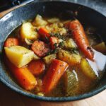 Close-up of a bowl of Roasted Winter Vegetable Soup with carrots, potatoes, onions and herbs.