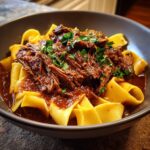 A bowl of Short Rib Ragu with Pappardelle pasta, garnished with fresh parsley.