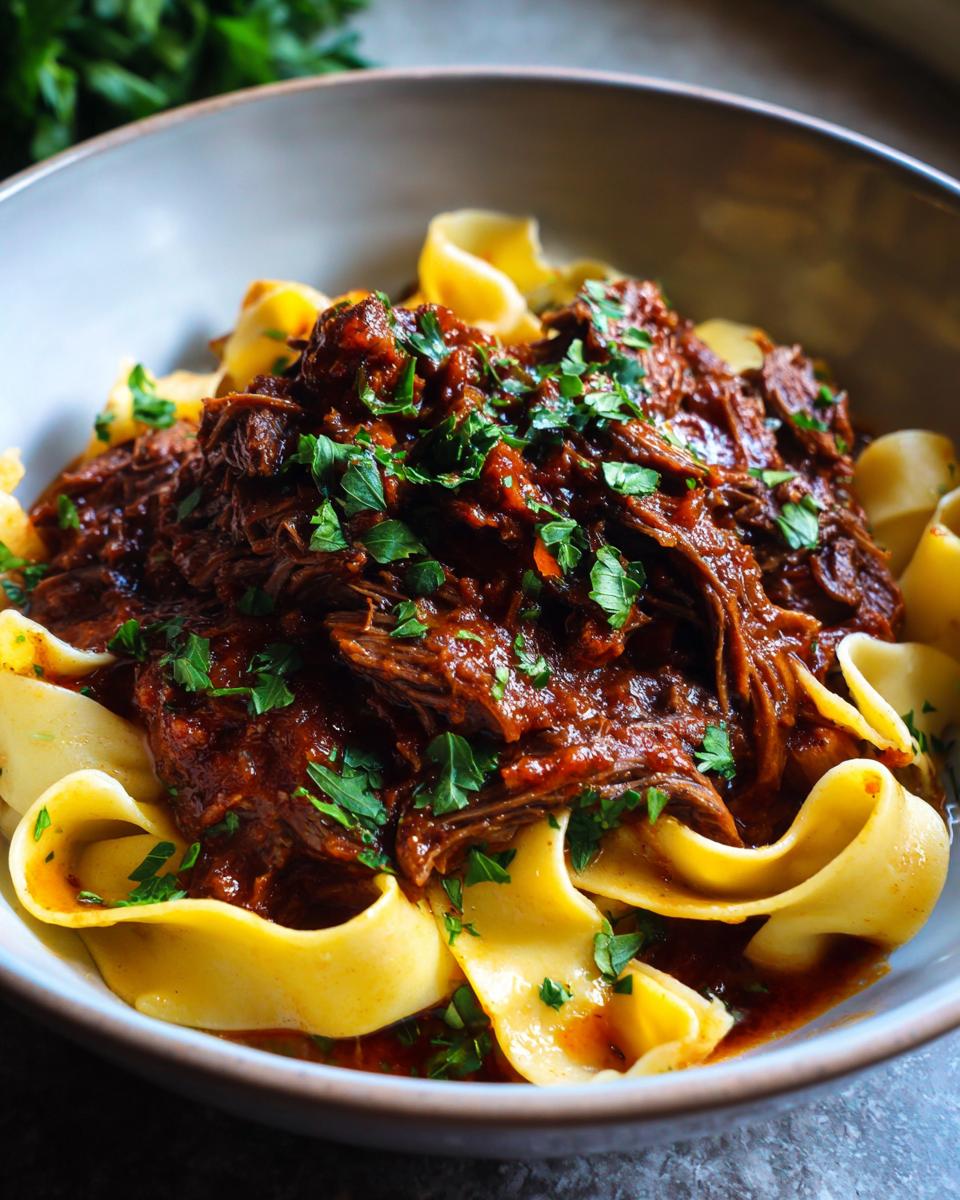 A bowl of Short Rib Ragu with Pappardelle, garnished with fresh parsley. Rich and flavorful.
