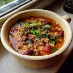 A flavorful bowl of Taco Rice Soup, featuring ground beef, rice, beans, and fresh green onions.