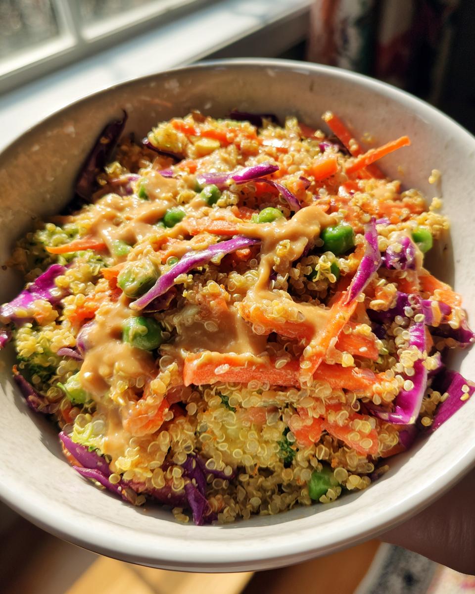 A colorful bowl of Thai Quinoa Salad with Peanut Dressing, featuring quinoa, carrots, cabbage, and peanut sauce.