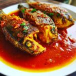 Three whole tilapias served in a vibrant roasted pepper sauce, garnished with herbs. Tilapia in Roasted Pepper Sauce recipe.