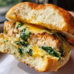 A close-up of a White Cheddar and Spinach Chicken Burger on a toasted bun, showcasing melted cheese and fresh spinach.