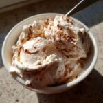 Bowl of homemade Baileys Ice Cream, topped with cocoa powder and a spoon.