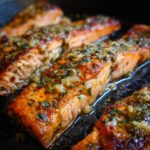 Close-up of Baked Lemon Garlic Salmon fillets, glistening with herbs and lemon garlic sauce.