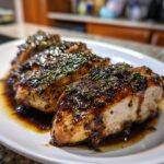 Three pieces of Balsamic Glazed Chicken with herbs on a white plate, ready to eat.
