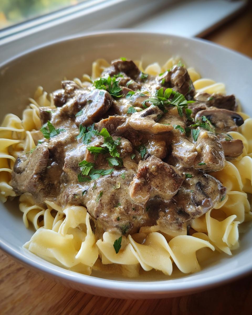 A delicious bowl of Beef Stroganoff, featuring tender beef, mushrooms, and a creamy sauce over egg noodles.