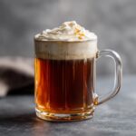 A mug of Chai Tea Latte topped with whipped cream and caramel drizzle.