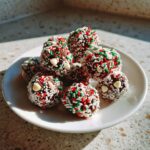 A plate of homemade Christmas Cookie Dough Truffles, decorated with festive red, green, and white sprinkles.