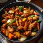 Close up of Easy Chicken Stir Fry with Veggies in a skillet, featuring chicken, onions, peppers, and carrots.